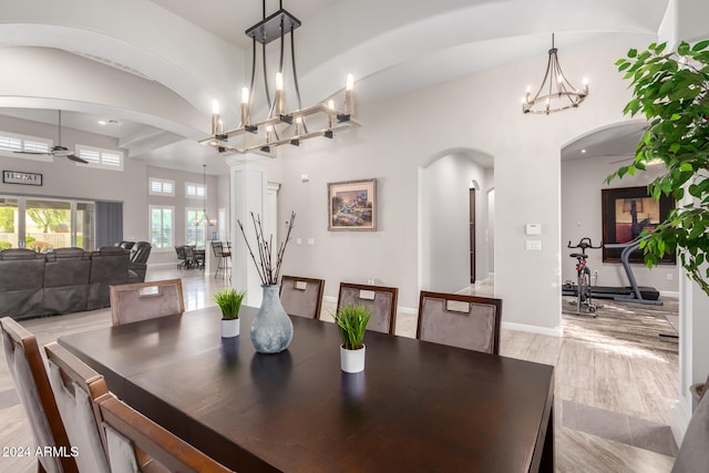 dining area with decorative columns, light wood-type flooring, and ceiling fan