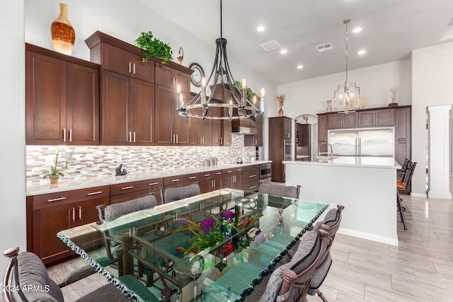 kitchen featuring a breakfast bar area, a chandelier, a kitchen island with sink, and pendant lighting