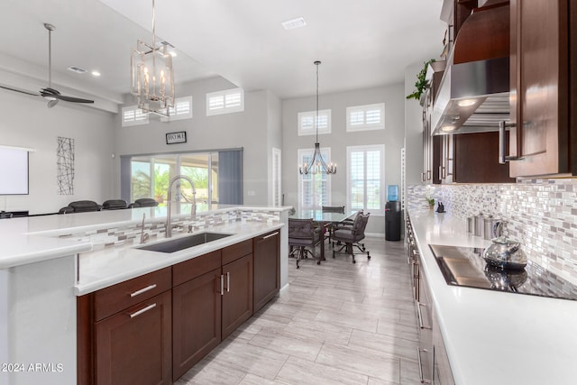 kitchen with tasteful backsplash, hanging light fixtures, dishwasher, a towering ceiling, and sink