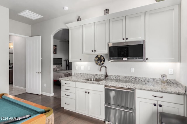 kitchen featuring sink, light stone countertops, white cabinetry, appliances with stainless steel finishes, and dark hardwood / wood-style flooring