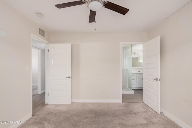 unfurnished bedroom with light colored carpet, ceiling fan, and ensuite bathroom