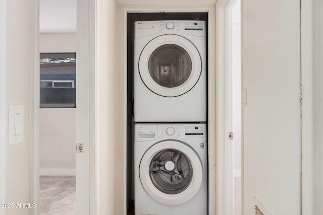 laundry room with stacked washer and clothes dryer and carpet flooring