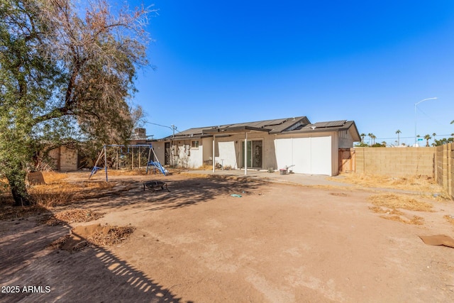 rear view of property with a playground and solar panels