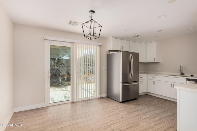 kitchen featuring sink, hanging light fixtures, stainless steel appliances, white cabinets, and light wood-type flooring