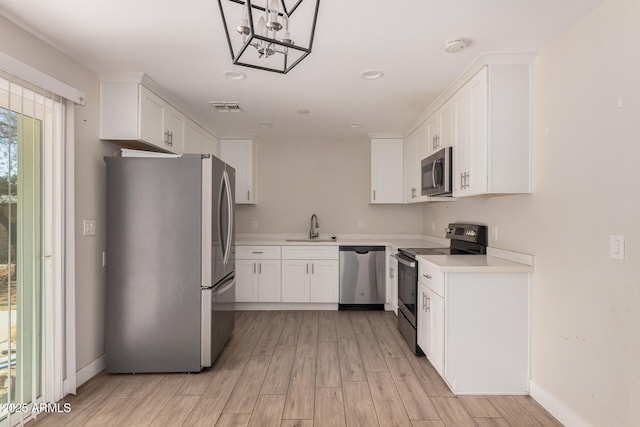 kitchen featuring stainless steel appliances, white cabinetry, sink, and light wood-type flooring