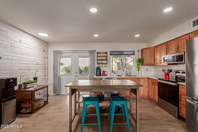 kitchen with appliances with stainless steel finishes, light countertops, french doors, a sink, and recessed lighting