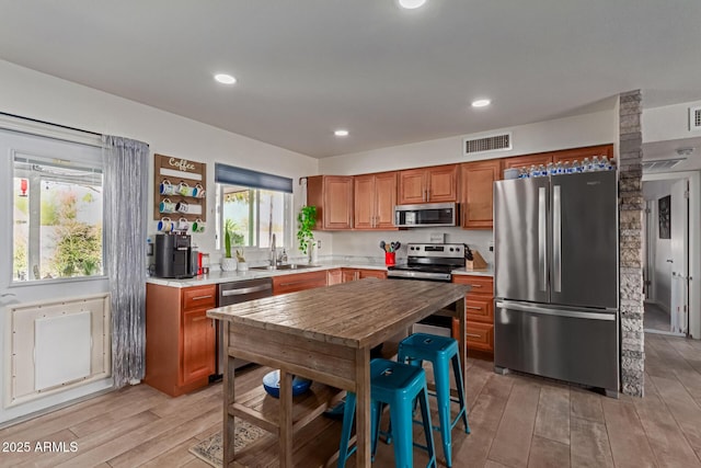 kitchen with visible vents, light wood-style flooring, appliances with stainless steel finishes, light countertops, and a sink