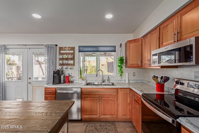 kitchen featuring appliances with stainless steel finishes, brown cabinets, french doors, a sink, and recessed lighting