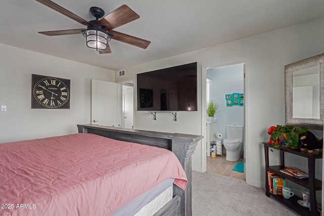 bedroom featuring a ceiling fan, ensuite bath, visible vents, and light colored carpet