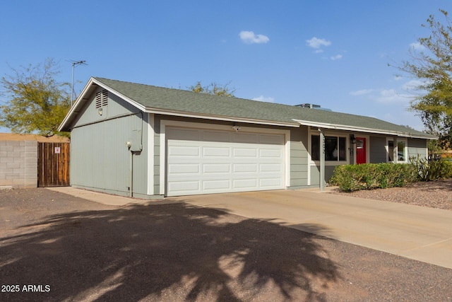 single story home with a garage, driveway, roof with shingles, and fence