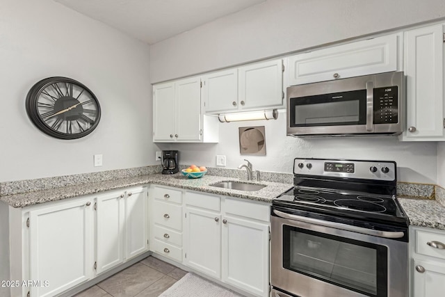 kitchen with stainless steel appliances, white cabinetry, a sink, and light stone counters