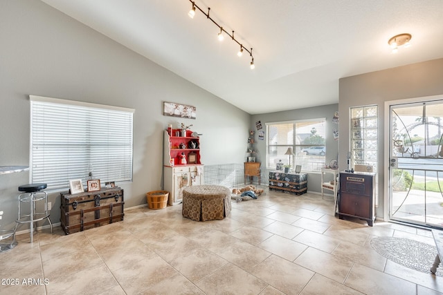 living area featuring track lighting, lofted ceiling, and light tile patterned floors