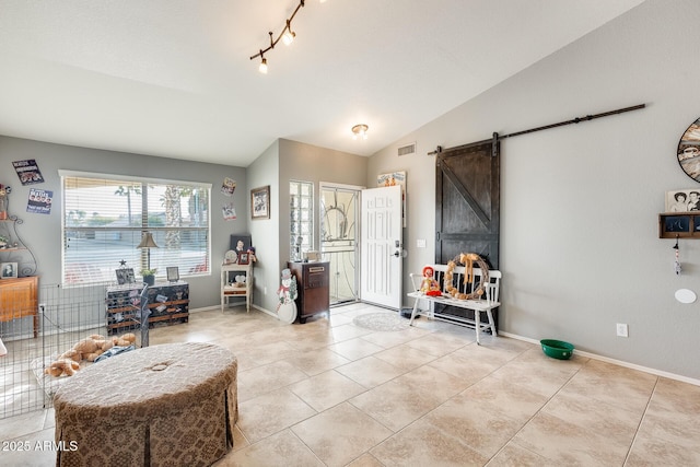 entryway with light tile patterned flooring, lofted ceiling, a barn door, and rail lighting