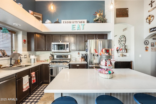 kitchen with stainless steel appliances, hanging light fixtures, sink, and decorative backsplash