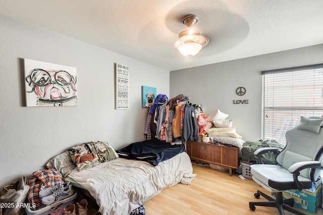 bedroom featuring ceiling fan, wood-type flooring, and a textured ceiling