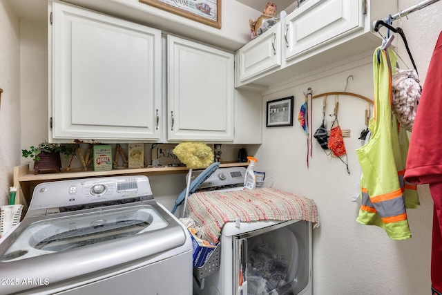 clothes washing area featuring cabinets and washer and dryer