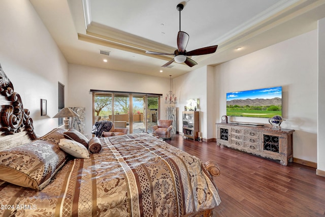 bedroom featuring access to outside, dark hardwood / wood-style floors, ceiling fan, and a tray ceiling