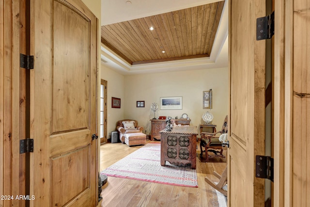 interior space featuring ornamental molding, a tray ceiling, wood ceiling, and light hardwood / wood-style floors