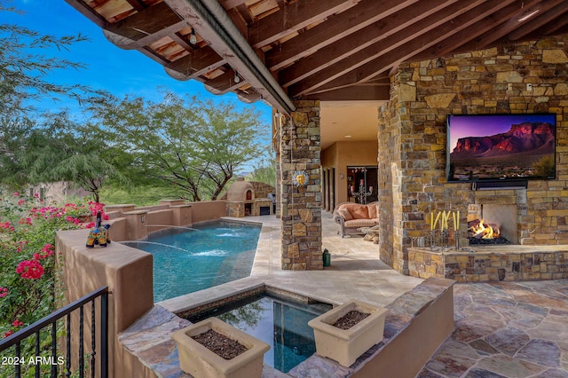 view of swimming pool with an outdoor stone fireplace, pool water feature, and a patio area