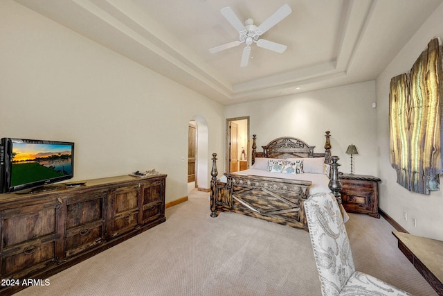 bedroom with light carpet, ceiling fan, and a tray ceiling