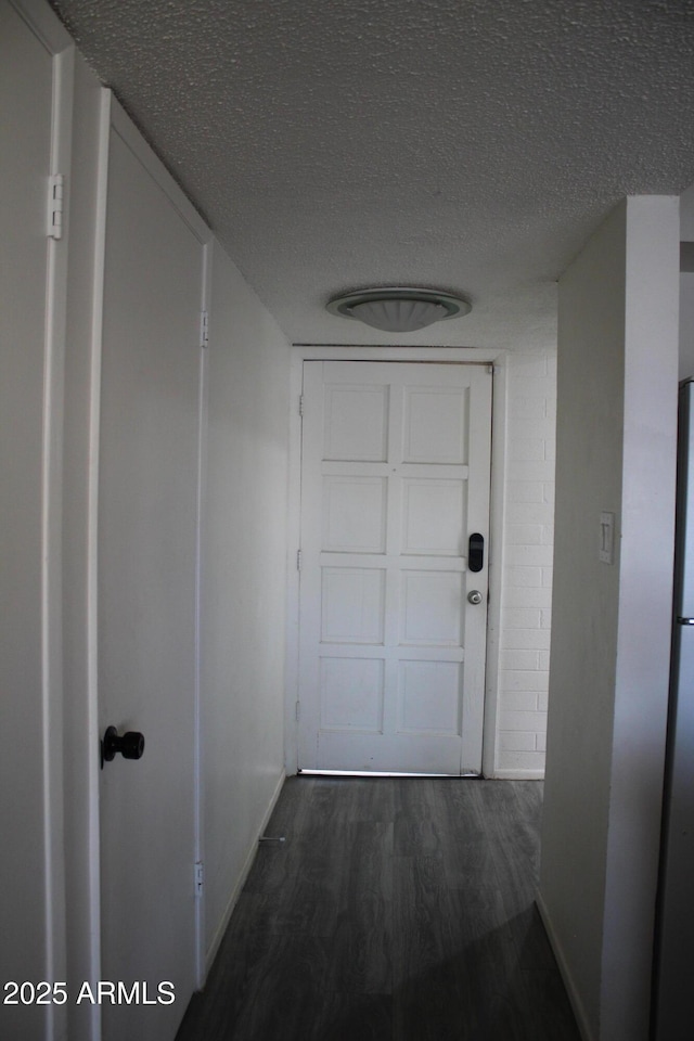 hall featuring dark wood-style floors, baseboards, and a textured ceiling