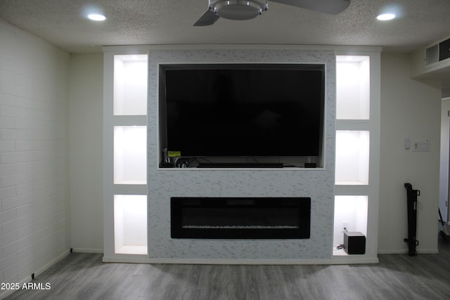 interior details with a fireplace, a textured ceiling, and wood finished floors