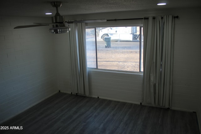 unfurnished dining area featuring a textured ceiling, a ceiling fan, and dark wood-style flooring