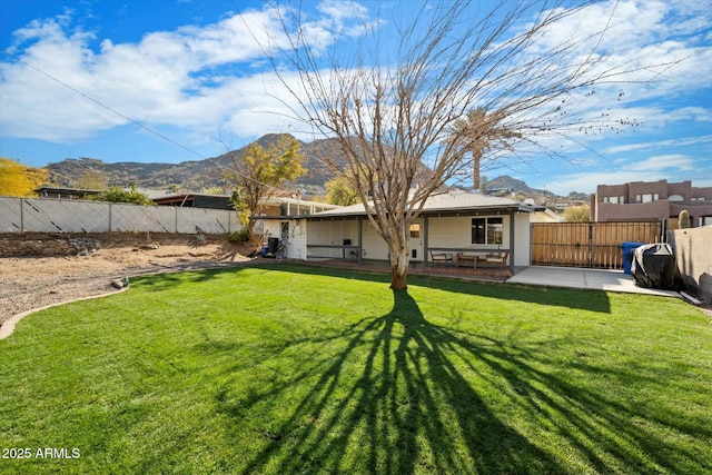 back of property featuring a mountain view, a yard, and a patio