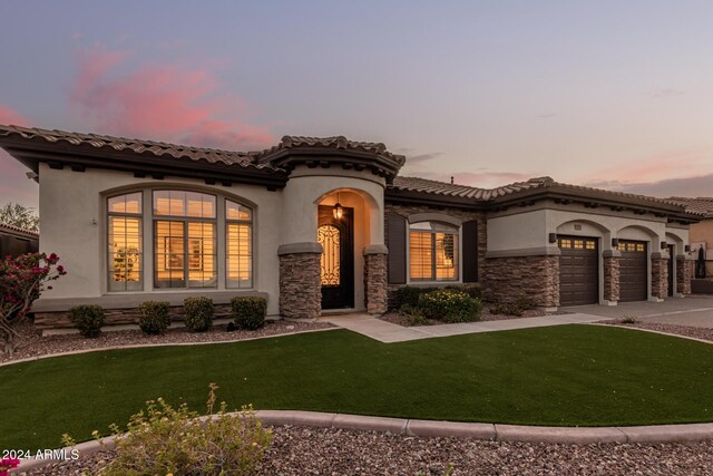 2717 W Nighthawk Way, Phoenix, AZ 85045 - mediterranean / spanish-style house with stucco siding, concrete driveway, a front lawn, a garage, and stone siding