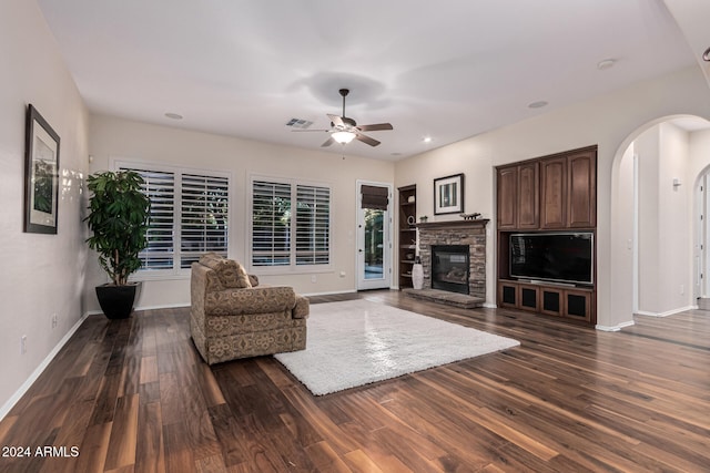 living room featuring dark hardwood / wood-style floors, ceiling fan, and a fireplace