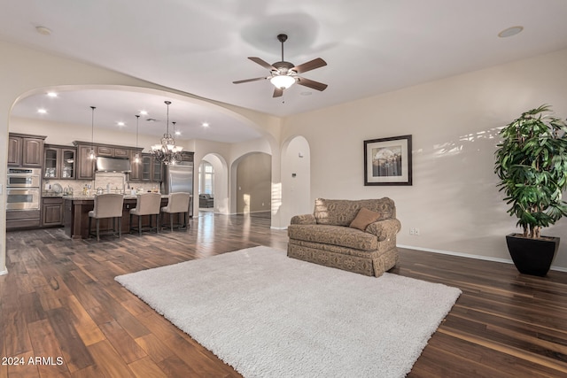 living room featuring ceiling fan with notable chandelier and dark hardwood / wood-style floors