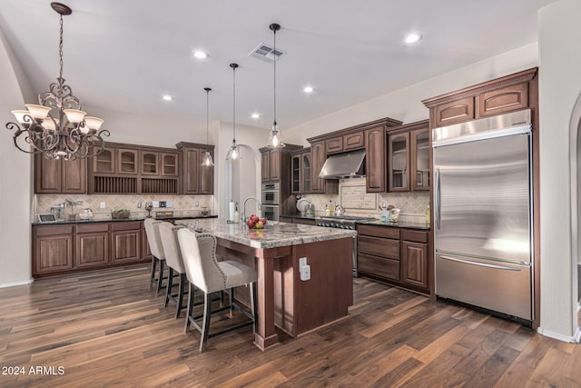 kitchen with pendant lighting, a large island, dark brown cabinetry, and appliances with stainless steel finishes