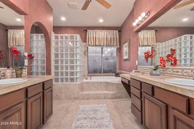 bathroom with tile patterned floors, tiled bath, ceiling fan, and vanity