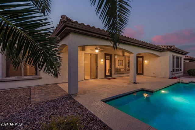 back house at dusk with ceiling fan and a patio