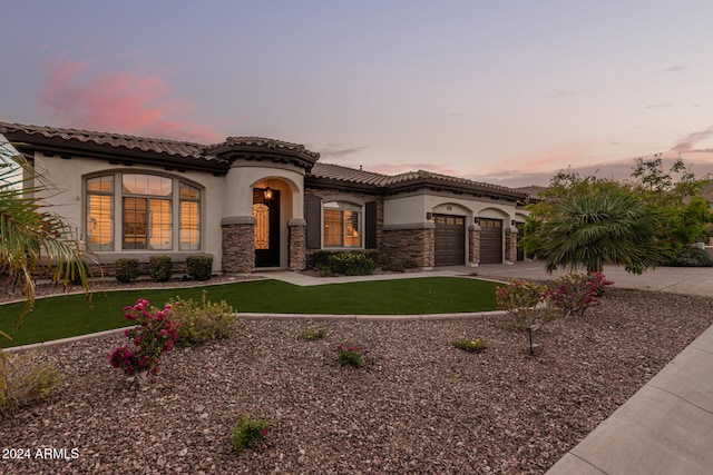 mediterranean / spanish-style home with a yard and a garage