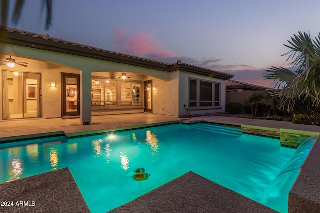 pool at dusk featuring a patio and ceiling fan