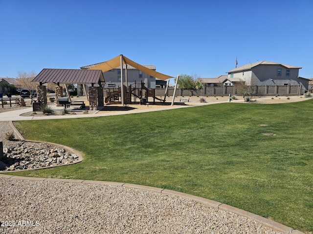 view of community with fence, playground community, and a yard