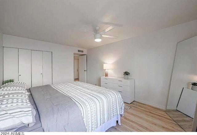 bedroom featuring a ceiling fan, a closet, baseboards, light wood finished floors, and visible vents