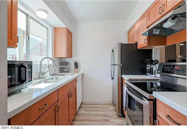 kitchen with light wood-type flooring, sink, backsplash, and stainless steel appliances