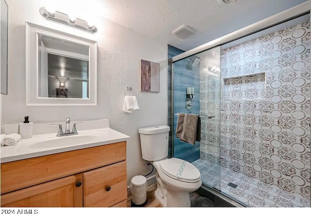 bathroom featuring a stall shower, toilet, visible vents, vanity, and a textured wall