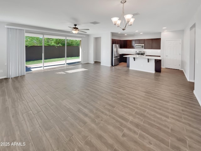 21081 W Almeria Rd, Buckeye, AZ 85396 - unfurnished living room with recessed lighting, wood finished floors, baseboards, and ceiling fan with notable chandelier