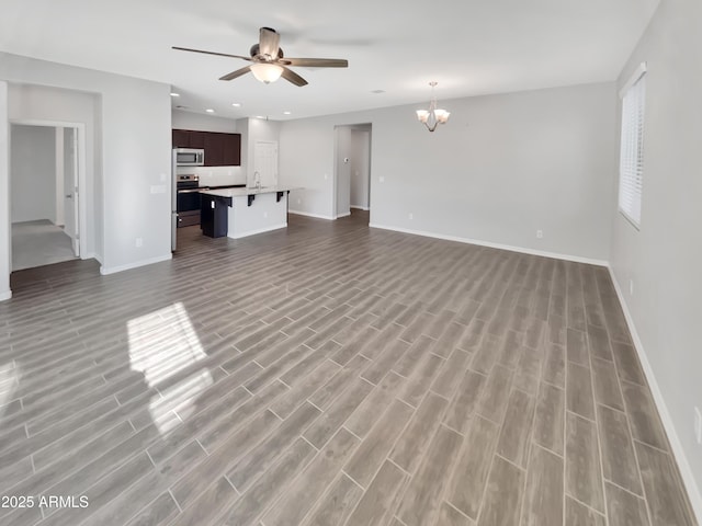21081 W Almeria Rd, Buckeye, AZ 85396 - unfurnished living room with ceiling fan with notable chandelier, baseboards, and recessed lighting