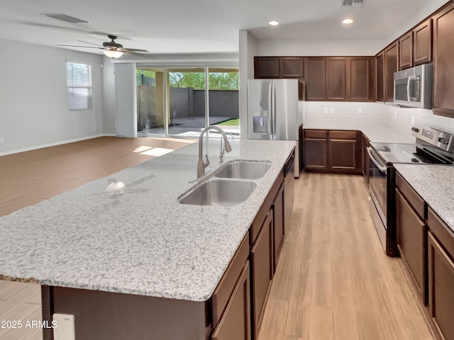 21081 W Almeria Rd, Buckeye, AZ 85396 - kitchen featuring light wood-type flooring, stainless steel appliances, a center island with sink, and a sink