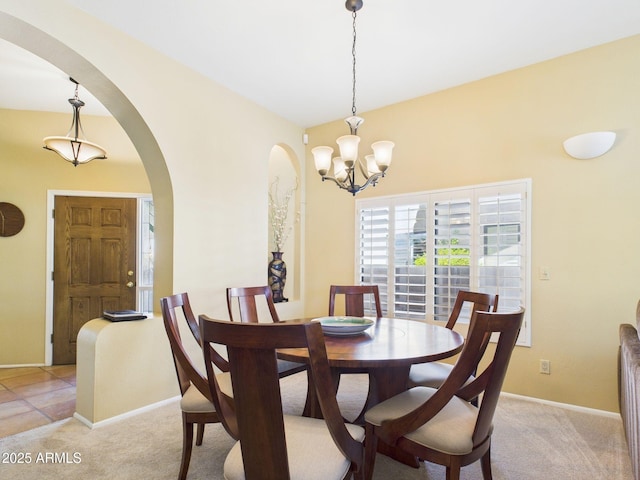 dining area with an inviting chandelier, arched walkways, baseboards, and light colored carpet