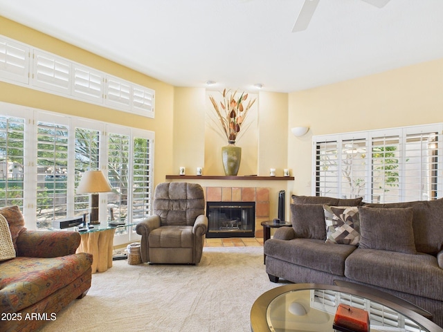 living room featuring carpet flooring, a tiled fireplace, and a ceiling fan