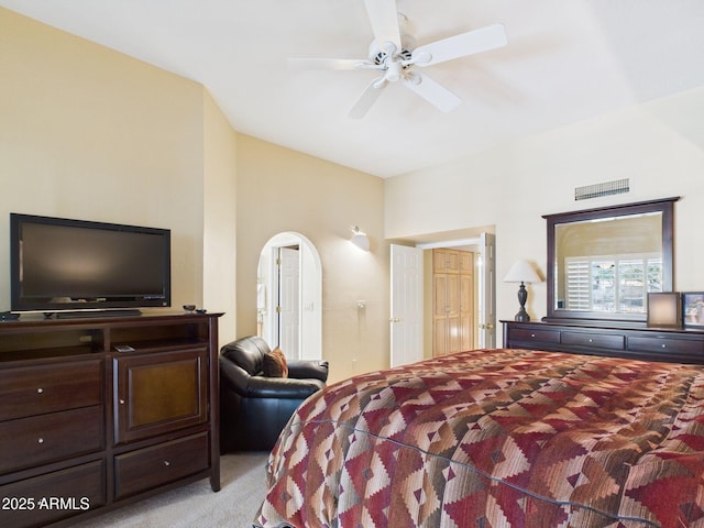 bedroom with a ceiling fan, arched walkways, light colored carpet, and visible vents