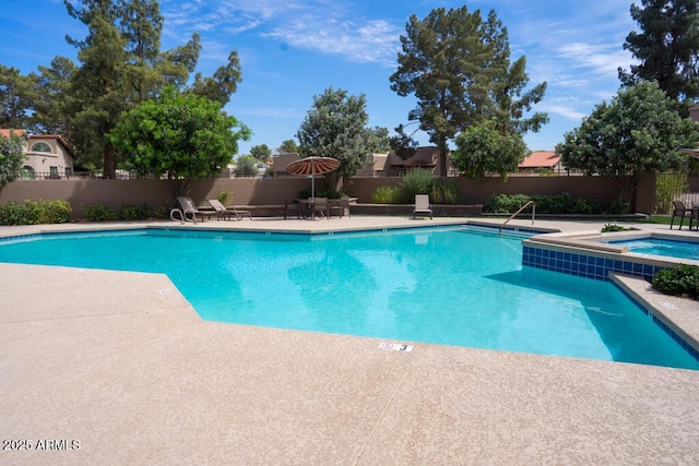 pool featuring a patio, fence, and a hot tub