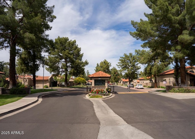 view of street featuring sidewalks, street lights, curbs, and a residential view