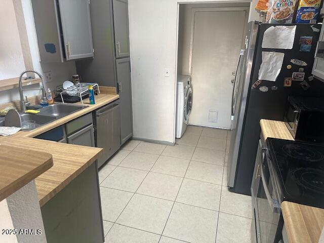 kitchen featuring a sink, light tile patterned floors, wood counters, and stainless steel appliances