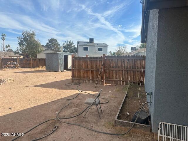 view of yard featuring a storage shed, an outbuilding, and a fenced backyard